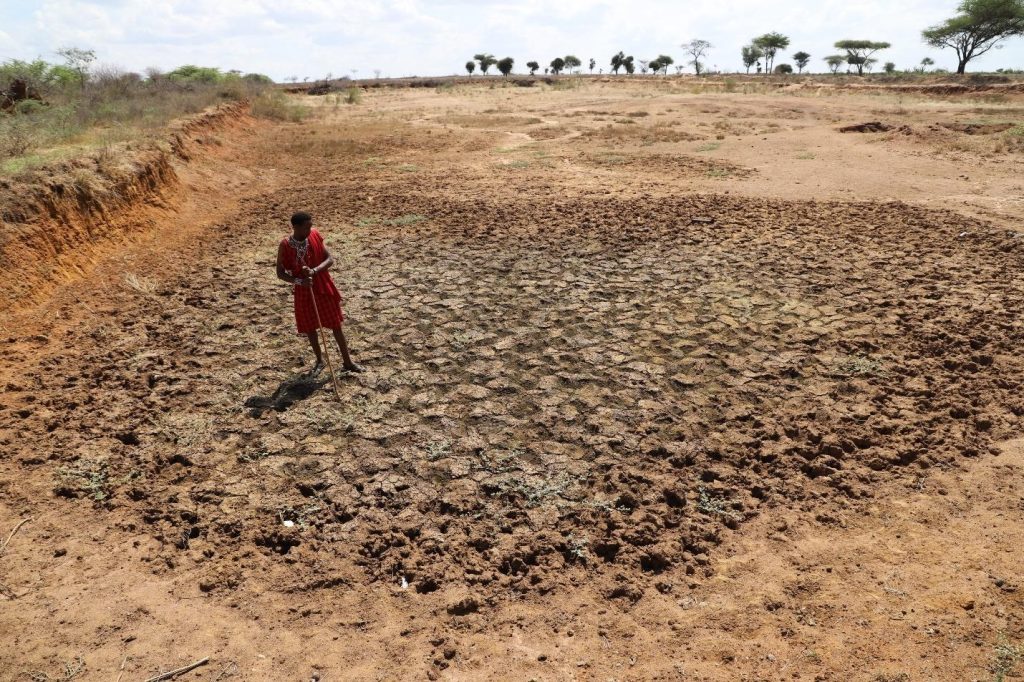 In Kenya’s Kajiado County, Simeon stands in a once-reliable waterhole that has now dried up. As a young pastoralist, he must travel increasingly long distances, up to 5 kilometers, to find water for his livestock. Photo Credits: Maureen Mutua